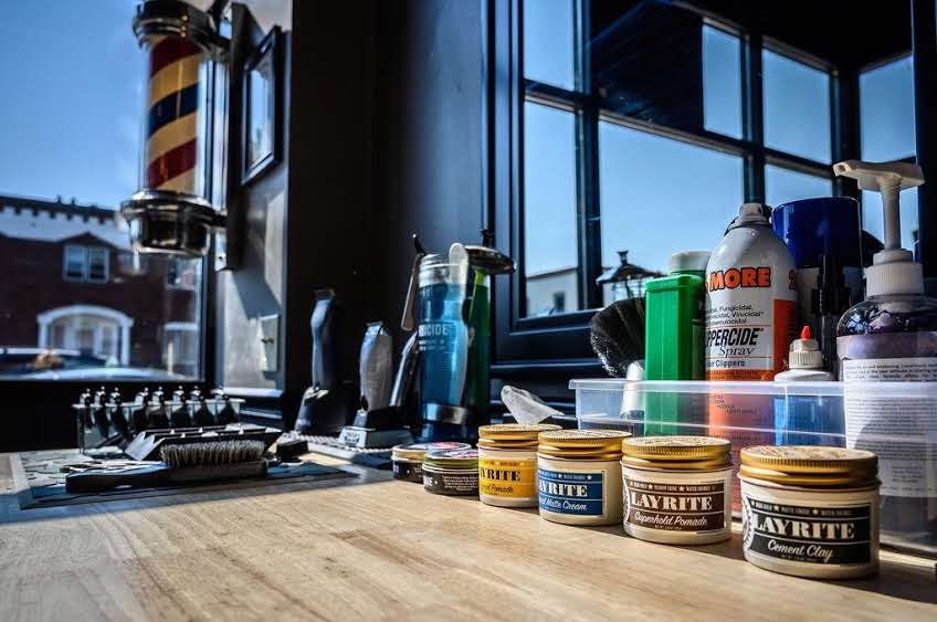 Barber workstation with pomades and barber pole in the window at Southside Barber Lounge
